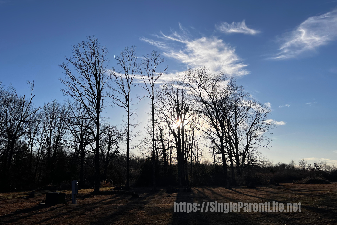 A breathtaking sunset with blue skies and scattered white clouds, overlooking a landscape free of snow after a heavy winter storm.